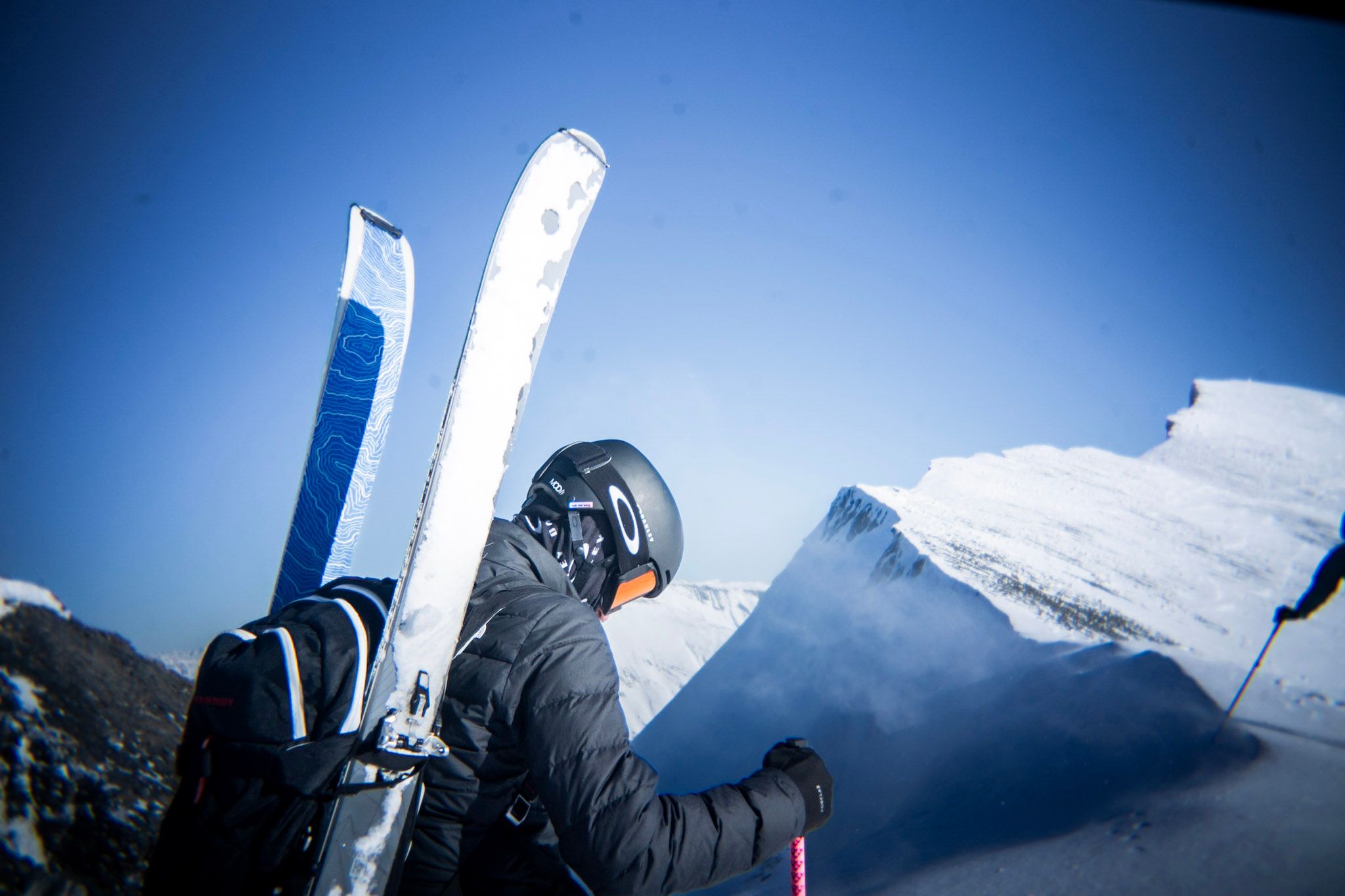 Freerider mit Ski am Rucksack steht auf einem verschneiten Grat