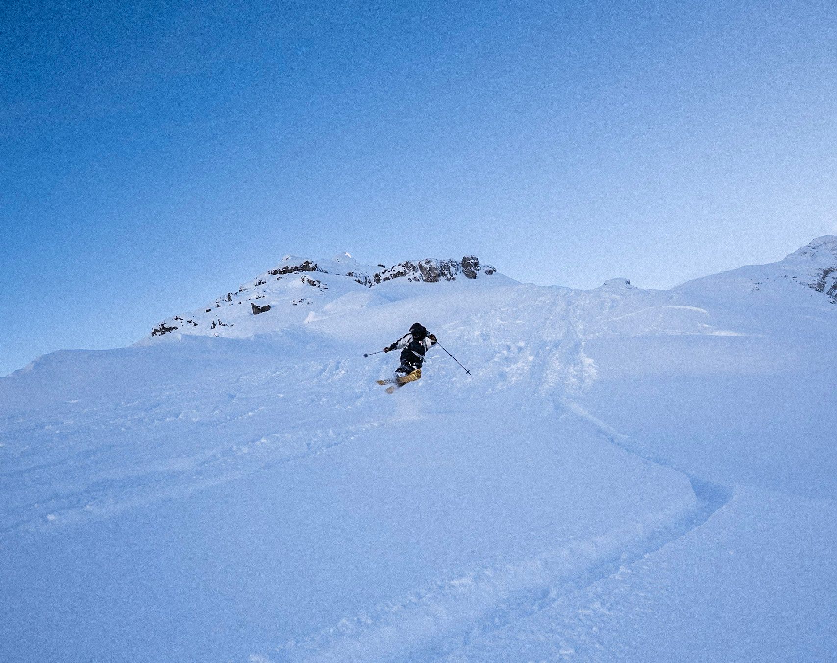Skifahrer zieht Spuren durch einen weiten, verschneiten Hang