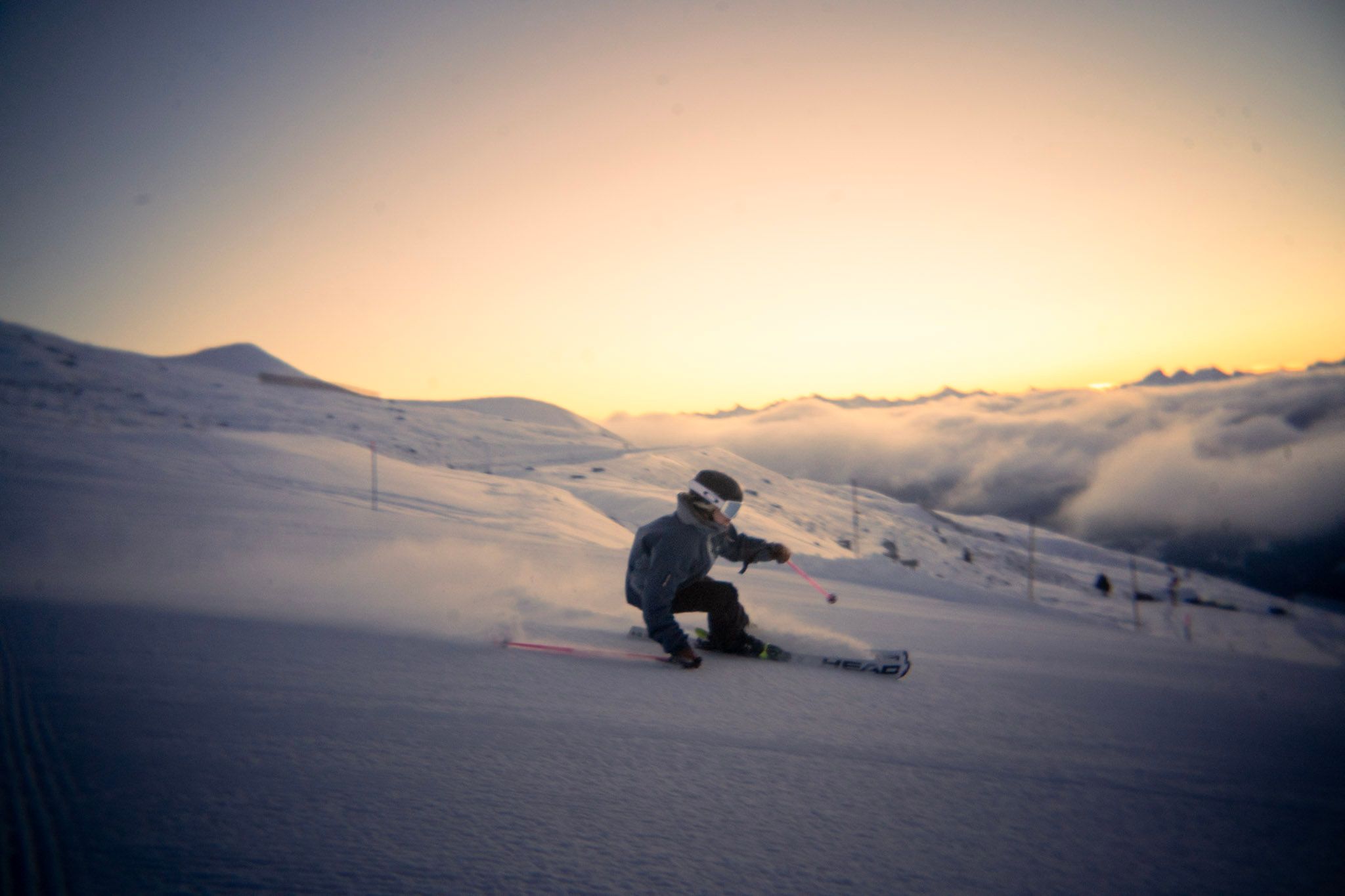 Skifahrer carvt bei Sonnenuntergang über dem Nebelmeer
